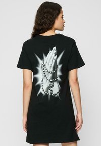 Robe t-shirt noire avec un imprimé graphique de mains jointes ornées de perles et d'un cœur dans le dos, à manches courtes et coupe décontractée.