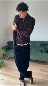 Bruine geribde trui met een halve ritskraag, gedragen over een wit overhemd. Gecombineerd met donkere broek en tweekleurige schoenen. Groene bank op de achtergrond.