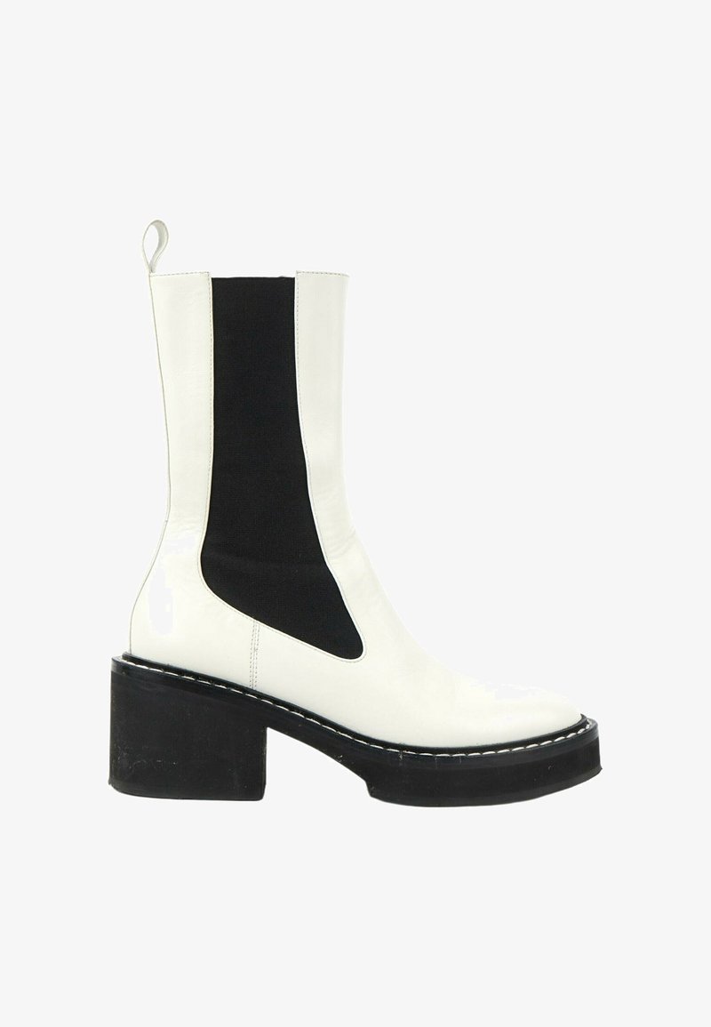 Bottine blanche en cuir avec panneau latéral élastique noir et talon bloc noir épais, avec une languette à l'arrière.
