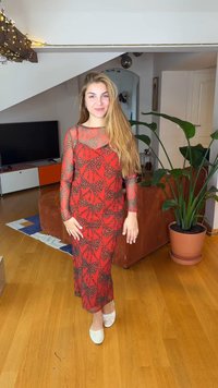 Κόκκινο δαντελένιο φόρεμα με μακριά διάφανα μανίκια, διακοσμημένο με σχέδιο φύλλων. Στυλιζαρισμένο με λευκά παπούτσια slip-on, σε ένα άνετο εσωτερικό περιβάλλον.