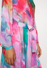 Túnica transparente y colorida con un patrón acuarelado fluido en rosa, verde y azul. Incluye un cinturón a juego y mangas largas.