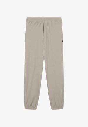 Beige Sporthose mit elastischem Bund und zulaufenden Bündchen. Verfügt über eine glatte Textur und ein Logo an der unteren Seite.