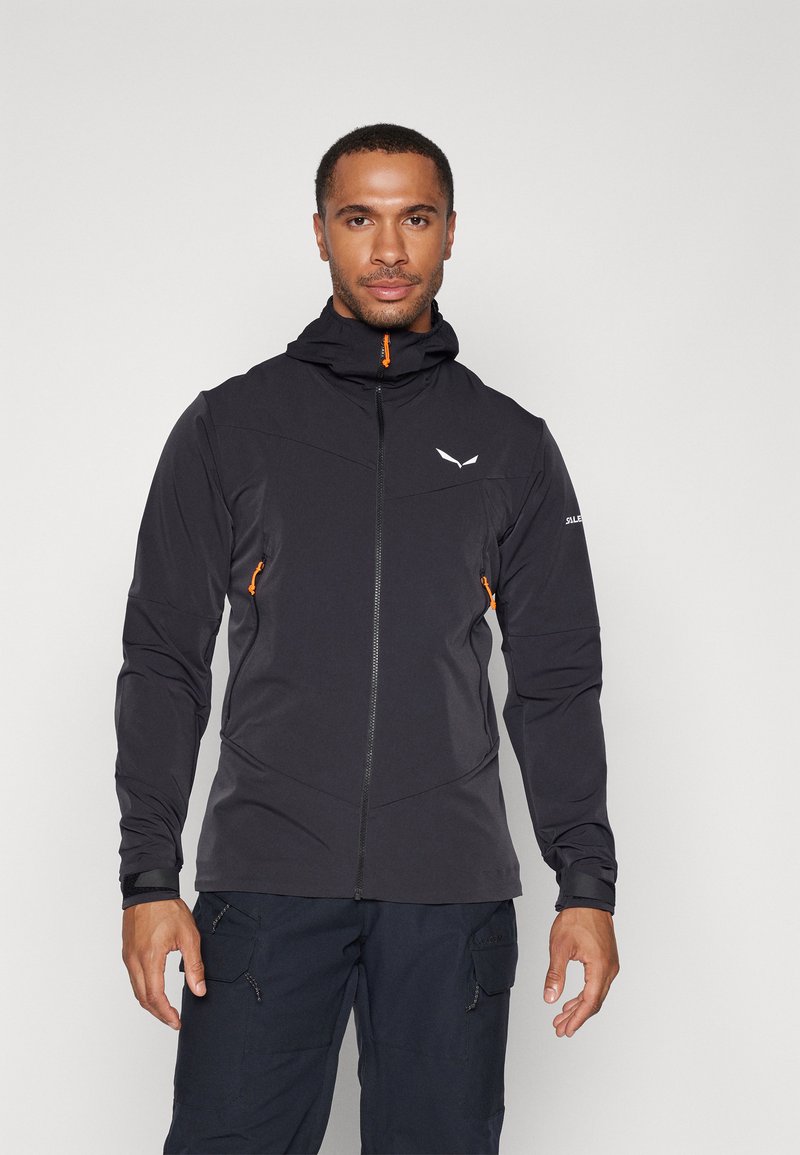 Veste extérieure noire avec fermeture éclair sur le devant, capuche et accents orange. Comprend un tissus texturé et une coupe ajustée, adaptée aux activités sportives.