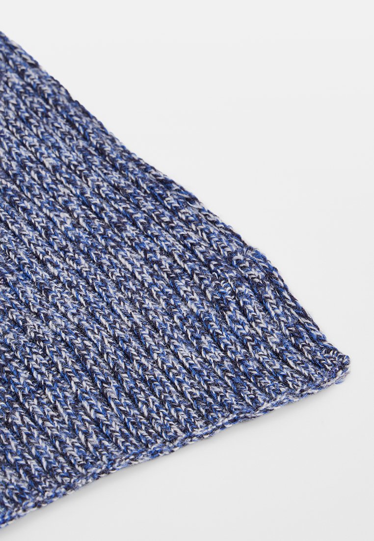 Tissu en tricot à motifs bleus et gris présentant un design texturé et côtelé, avec des coutures visibles et une finition douce.