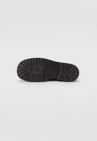 Semelle de chaussure en caoutchouc noir avec un motif texturé, comportant des rainures et des détails en forme d'étoile pour l'adhérence. Fini lisse dans l'ensemble.