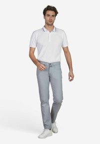 Polo shirt blanc avec un col présentant des rayures navy, associé à un pantalon slim gris clair et des baskets blanches. Tissu doux, design décontracté.