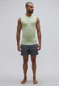 Sleeveless light green athletic top with black logo, paired with gray shorts. Smooth texture, fitted design, and minimalist style.