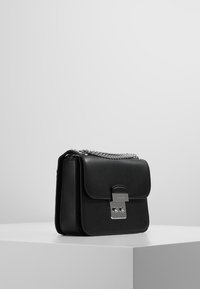 Borsa in pelle nera con un design strutturato. Caratterizzata da una chiusura in argento, tracolla a catena e texture liscia. Forma rettangolare compatta.