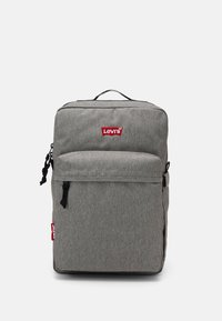 Szary plecak z materiału o prostokątnym kształcie, z uchwytem na górze i przednią kieszenią na zamek. Posiada czerwone logo Levi's i czarne uchwyty zamka.
