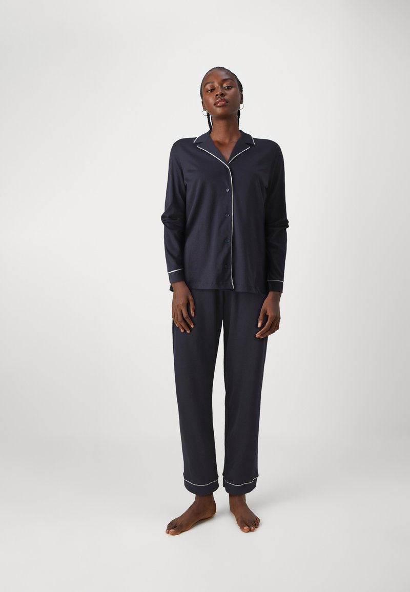 Marinblå pyjamasset i mjukt tyg som har en knapp-up skjorta med vita detaljer och raka byxor med uppvikta fållar.