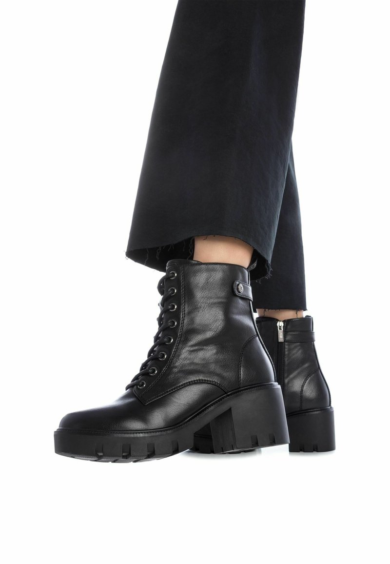 Botas de tobillo de cuero negro con cordones en la parte delantera y tacón ancho, con cremallera lateral y suela texturizada para un mejor agarre.