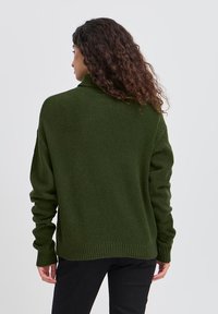 Maglione oversized di colore verde scuro con colletto alto, polsini e orlo a costine. Texture morbida, dotato di una vestibilità rilassata, mostrato di spalle.