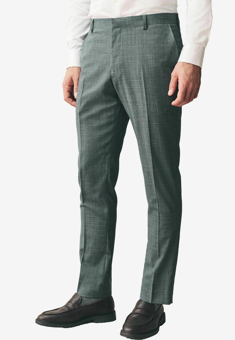 Grå teksturerede bukser med en skræddersyet pasform, der har flad front og sidelommer. Kombineret med mørkebrune loafers.