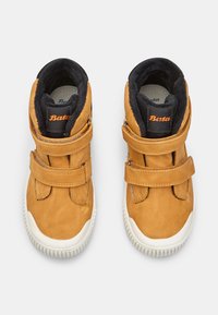 Scarpe alte in pelle scamosciata color cognac con due strap in Velcro, fodera nera e suole in gomma bianche. Il marchio "Bata" è visibile sulla linguetta in arancione.