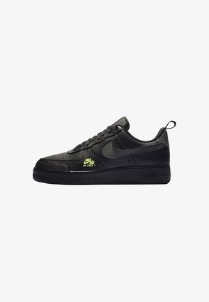Czarny sneaker Nike Air Force 1 ze skóry o fakturze, czarnym logo Swoosh, sznurowanym przodem i małym neonowożółtym logo "Nike Air Force 1" po boku.