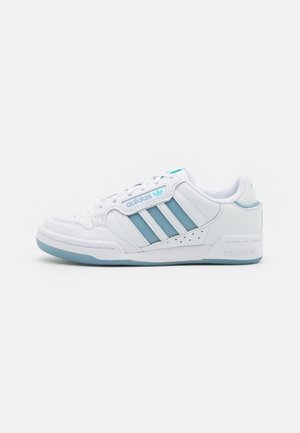 Biała tenisówka Adidas z jasnoniebieskimi paskami i logo, niska konstrukcja, z przodu sznurowana i jasnoniebieską podeszwą, widok z boku.