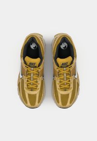 Baskets Nike Vomero 5 jaunes avec matériau en maille et synthétique, accents gris, conception à lacets et semelle en caoutchouc.