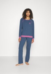Blauwe pyjama set van zachte stof. Langsleeve top met roze accenten en hart broderie. Bijpassende broek met een relaxte pasvorm.