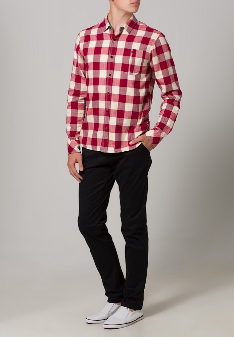 Rood-wit geruite blouse met lange mouwen en een knoopsluiting kraag, gecombineerd met zwarte broek en witte sneakers.