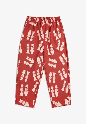 Rode elastische broek met een abstract patroon, gekenmerkt door lichtroze geometrische vormen en eenvoudige gezichten die over de stof zijn verspreid.