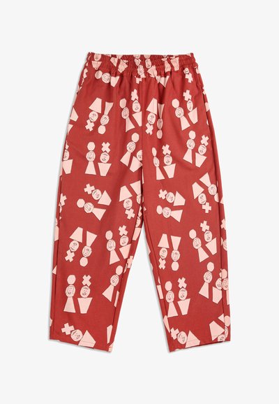 Červené kalhoty s elastickým pasem a abstraktním vzorem, který obsahuje světle růžové geometrické tvary a jednoduché tváře rozptýlené po látce.
