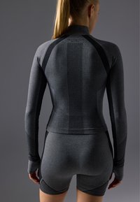 Haut de sport ajusté à manches longues et short en gris foncé avec des détails en mesh et des accents noirs, mettant en avant un design aérodynamique et une texture lisse.