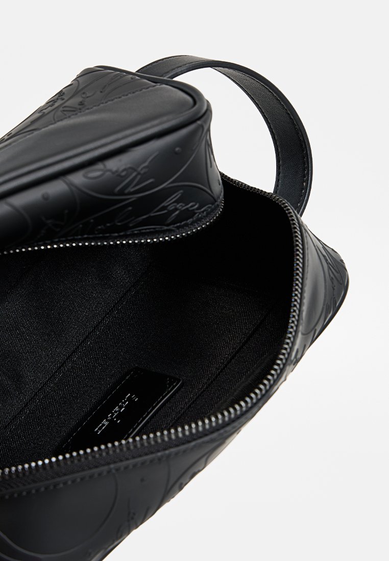 Borsa in pelle nera con motivi in rilievo, chiusura con zip e un manico singolo. Interno foderato in un morbido tessuto nero.