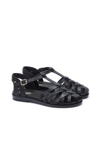 Sandalias negras hechas de material sintético con tiras entrelazadas, diseño de tira en T, hebilla ajustable, suela plana y estilo de punta abierta.