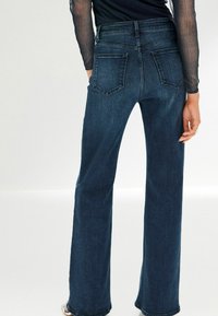 Tummansinisiä korkeavyötäröisiä farkkuja, joissa on suora lahje, taka-taskut ja siisti helma. Valmistettu denim-kankaasta.