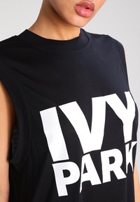 Czarny bezrękawnik z bawełny z odważnym białym napisem "IVY PARK" na przodzie; okrągły dekolt i materiał o fakturze na ramionach.