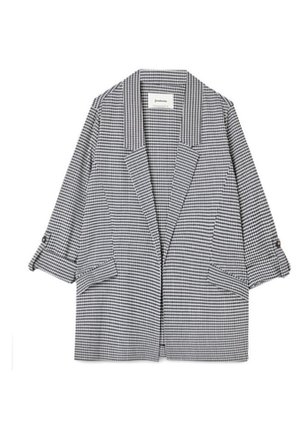 Blazer de cuadros en blanco y negro con solapas anchas, mangas tres cuartos remangadas aseguradas con tiras de botón y bolsillos delanteros con solapa.