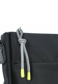 Borsa in tessuto nero con texture, dotata di zip, caratterizzata da un laccio bianco e nero annodato con punte gialle come accentuazione per la trazione.