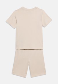 Σετ από μπεζ κοντομάνικη μπλούζα και σορτς μέχρι το γόνατο, απλωμένα επίπεδα, πίσω όψη, απλό σχέδιο με στρογγυλή λαιμόκοψη.
