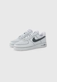 Baltas ādas sporta apavi ar pelēkiem akcentiem, ar noapaļu purngali, perforētiem detaļām, taisnām šņorēm un ikonisko Nike simbolu. Strukturēta zolīte.