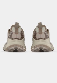 Chaussures de randonnée beiges avec une tige texturée, un talon renforcé et une semelle en caoutchouc durable. Elles sont dotées d'une languette d'aide au retrait et de motifs géométriques marron subtils.