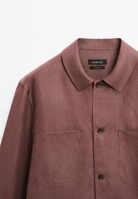 Bordeaux kleurige button-up shirt met een kraag, twee borstzakken en donkere knopen. De stof heeft een gestructureerde weving en een licht gestructureerd ontwerp.