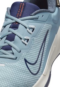 Baskets de sport bleu clair avec un dessus texturé, lacets bleu foncé et logo contrasté. Comprend un col rembourré et un talon renforcé.