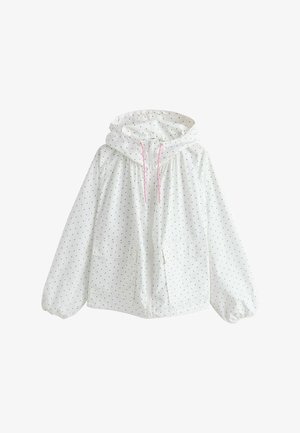 Veste blanche à capuche avec des pois noirs, zipper frontal, cordons de serrage roses, poignets élastiques et deux poches avant.