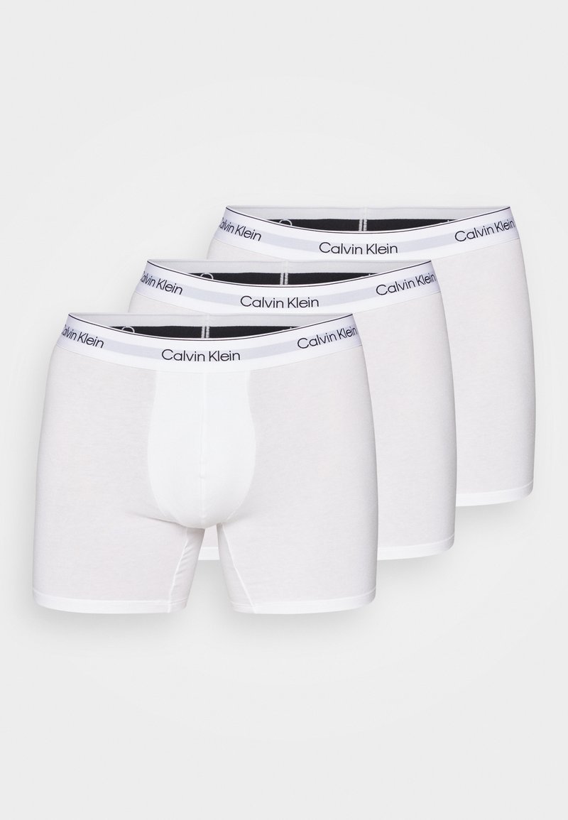 Caleçons boxers en coton blanc de Calvin Klein, avec une ceinture logo noire, longueur mi-cuisse et texture lisse. Ensemble de trois.