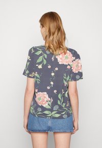 Camisa de manga curta floral em tecido azul marinho escuro, com grandes peónias cor-de-rosa e folhas verdes, com um corte reto e textura suave.