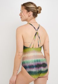 Maillot de bain une pièce multicolore avec un motif tie-dye en vert, rose et bleu. Dispose de bretelles croisées et d'un léger éclat.