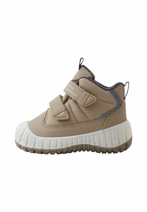 Stivaletto impermeabile beige per bambini con due strisce in velcro, suola spessa bianca testurizzata e linguette nere sul tallone e sulla lingua.