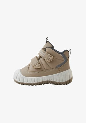 Beiger wasserdichter Kinderstiefel mit zwei Klettverschlüssen, dicker weißer texturierter Sohle und schwarzen Zuglaschen an Ferse und Zunge.