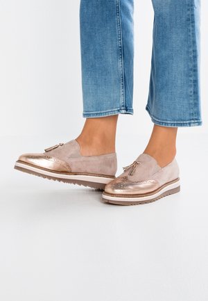 Slip-On-Loafer mit roségoldfarbenen Metallkappen und Wildleder-Obermaterial, getragen zu kurzen blauen Jeans vor hellem Hintergrund.