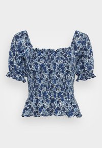 Blå blommig topp med puffärmar, smockad byst och peplumslut. Har en blandning av mörka och ljusa blå blommor på en vit bakgrund.