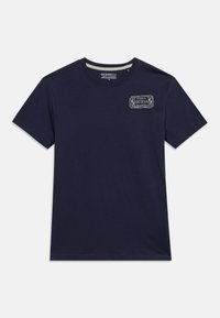 Μπλε ναυτικό κοντομάνικο t-shirt με μικρό λευκό λογότυπο "GUESS" στο αριστερό άνω μέρος του στήθους και λαιμόκοψη στρογγυλής γραμμής.