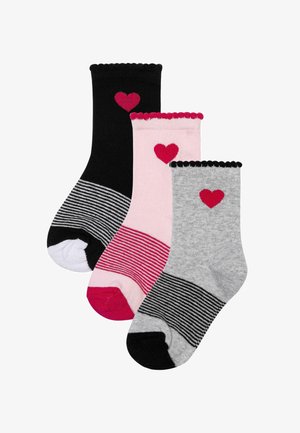 Trois chaussettes pour enfants en noir, rose et gris, chacune avec un cœur rouge près du haut et des motifs rayés sur la zone des pieds.