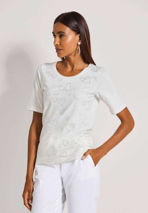 Wit shirt met korte mouwen en hartpatronen in een subtiele glans. Gladde textuur, ronde halslijn, gecombineerd met witte broek.