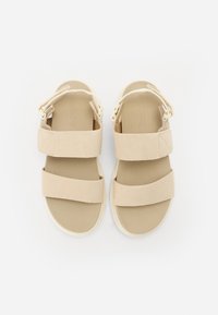 Lysebeige sandaler med to brede stropper, en teksturert overflate og en polstret såle. Inkluderer justerbar hælkrok for sikker passform.
