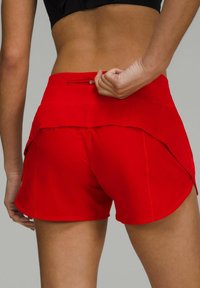 Bermudas deportivas rojas con un diseño en capas, que incluyen un bolsillo con cremallera oculta y una tela suave y ligera.